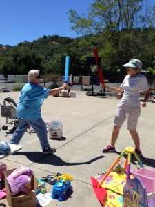 Our director Marlene shows off some fencing skills with a local community member (and friend to Grace) who attended the sale. 